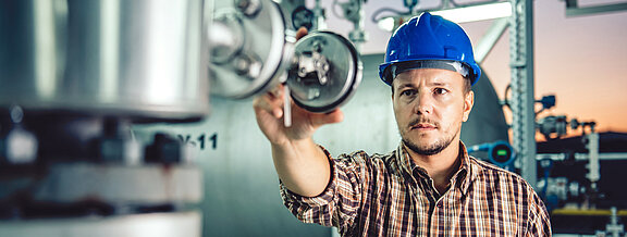 Worker at the measuring device, helmet, blue  